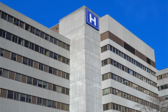 Large concrete building with H sign for hospital accessibilité hopital